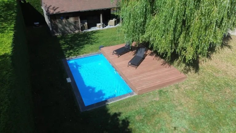 Zwembad met mobiel terras dat open ligt in groene tuin.